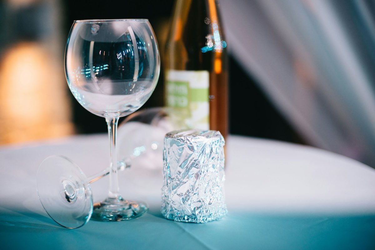 A wedding glass wrapped in foil, ready to be broken, beside a bottle of kiddush wine